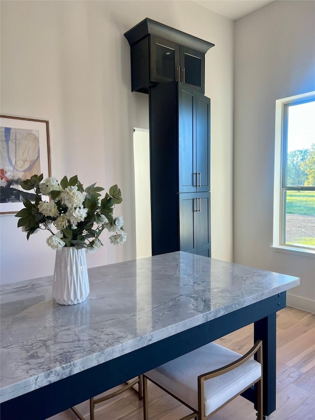 kitchen featuring a kitchen bar, light stone countertops, a wealth of natural light, and light hardwood / wood-style flooring