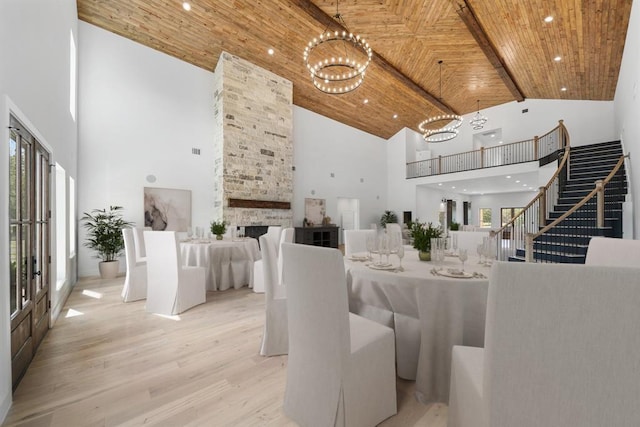 dining area with a fireplace, beamed ceiling, high vaulted ceiling, and wooden ceiling