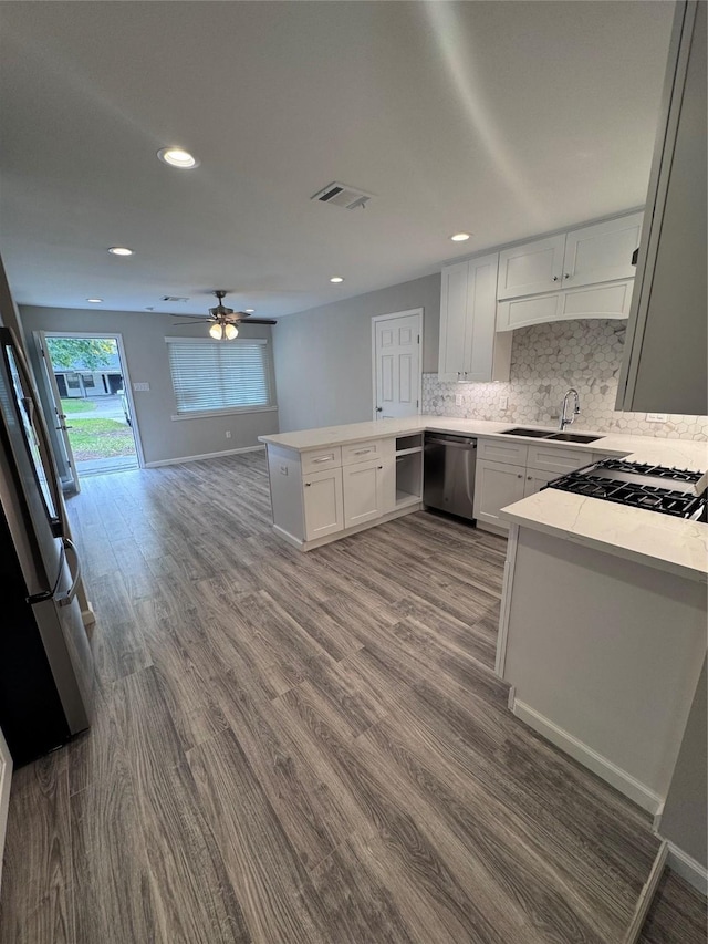 kitchen featuring hardwood / wood-style floors, white cabinets, stainless steel appliances, sink, and kitchen peninsula