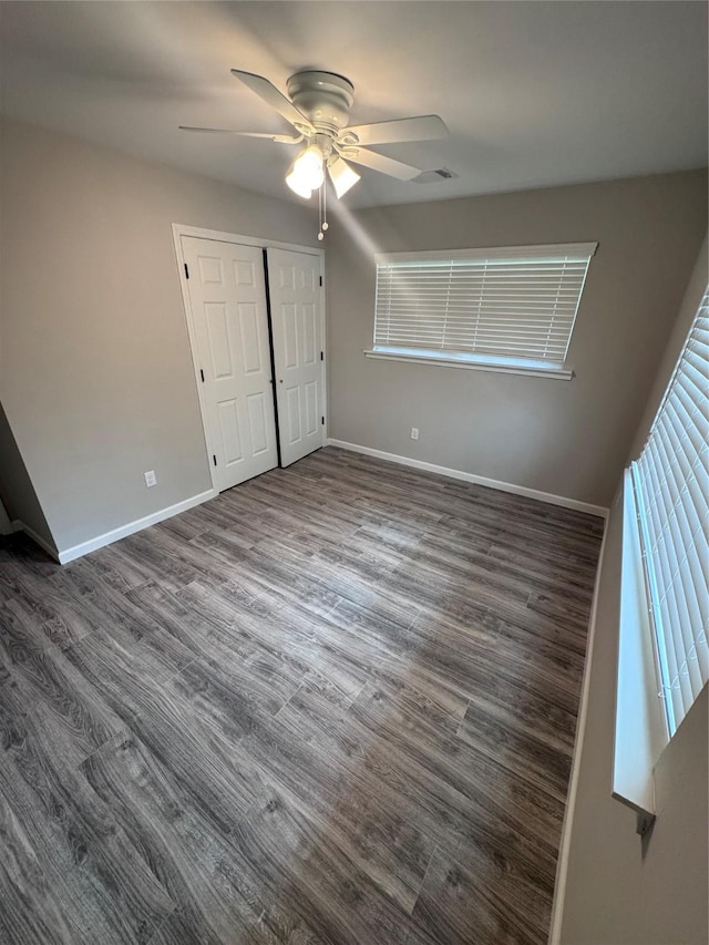 unfurnished bedroom featuring dark wood-type flooring, ceiling fan, and a closet