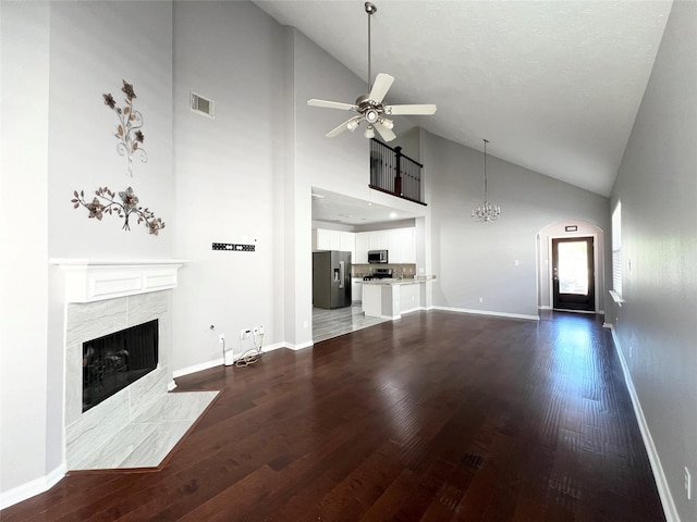 unfurnished living room with dark hardwood / wood-style flooring, high vaulted ceiling, and a tiled fireplace