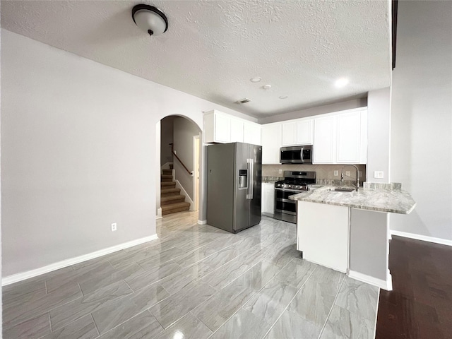 kitchen with white cabinetry, sink, stainless steel appliances, kitchen peninsula, and a textured ceiling