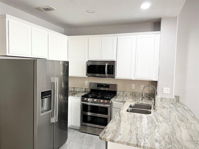 kitchen featuring appliances with stainless steel finishes, backsplash, a textured ceiling, sink, and white cabinets