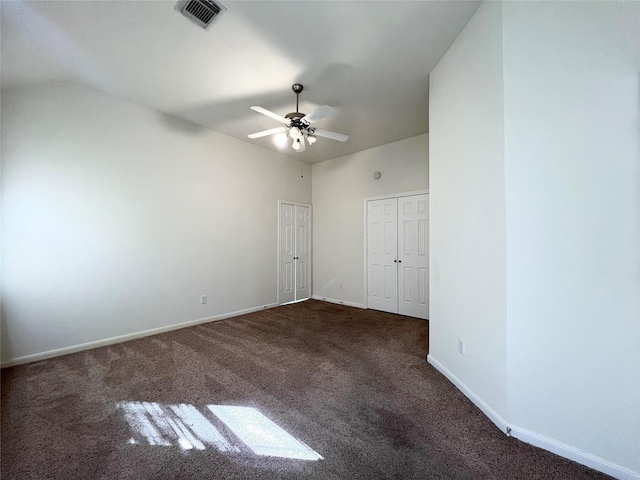 empty room with ceiling fan, vaulted ceiling, and dark colored carpet