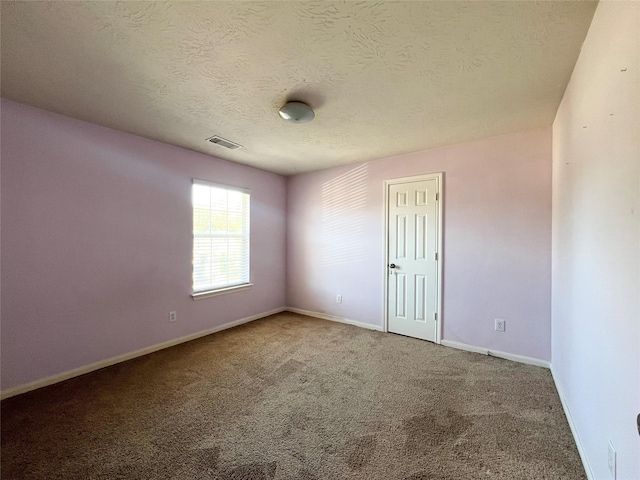 carpeted empty room with a textured ceiling