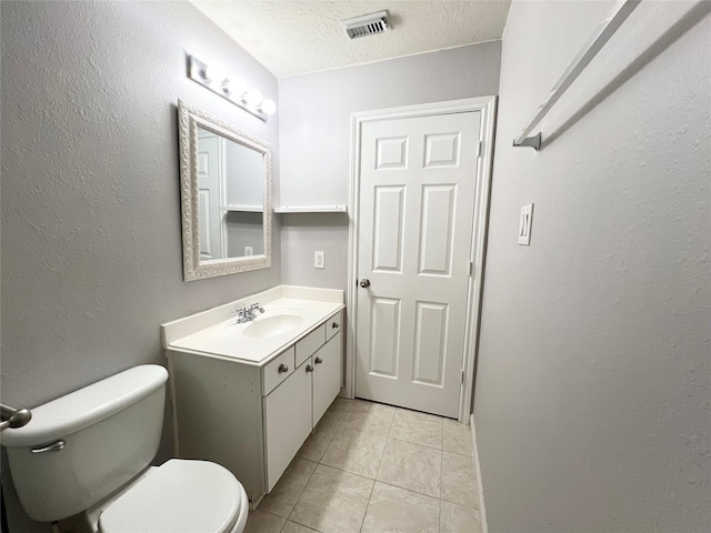 bathroom with tile patterned floors, vanity, a textured ceiling, and toilet