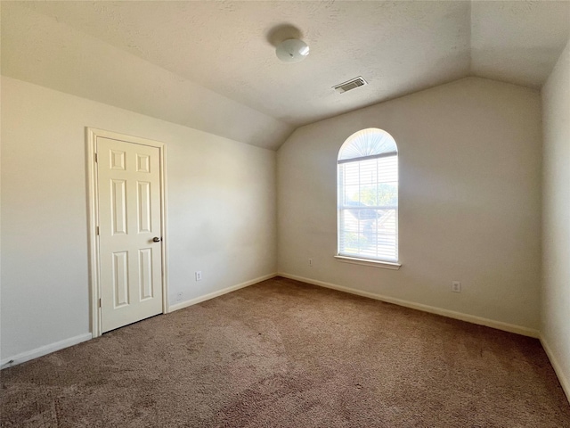 spare room with carpet, lofted ceiling, and a textured ceiling