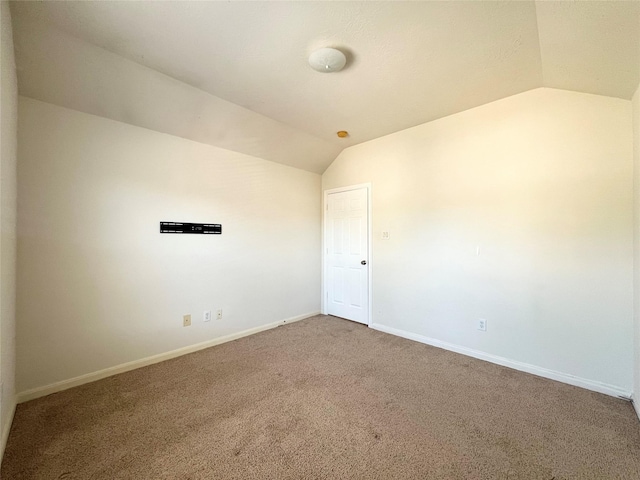 spare room with carpet flooring and vaulted ceiling