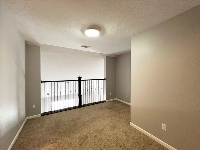 carpeted spare room with a textured ceiling