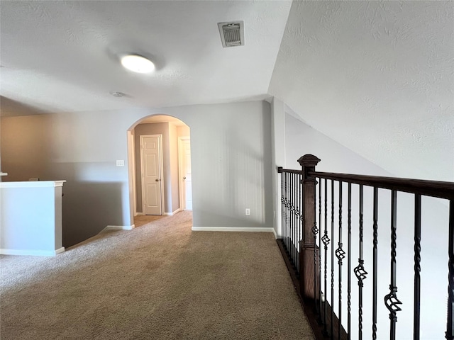 corridor featuring carpet flooring, a textured ceiling, and vaulted ceiling