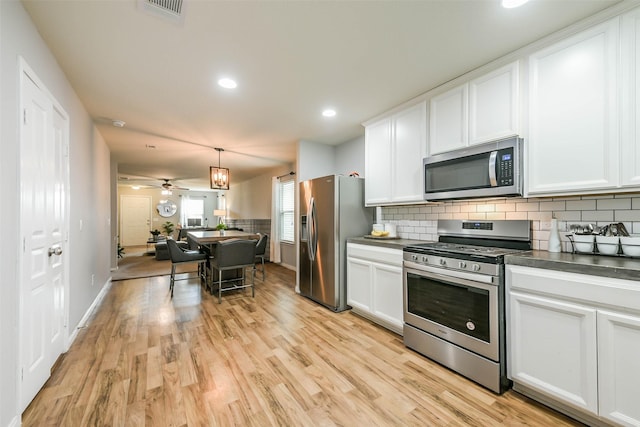 kitchen with white cabinetry, ceiling fan, stainless steel appliances, light hardwood / wood-style flooring, and decorative light fixtures