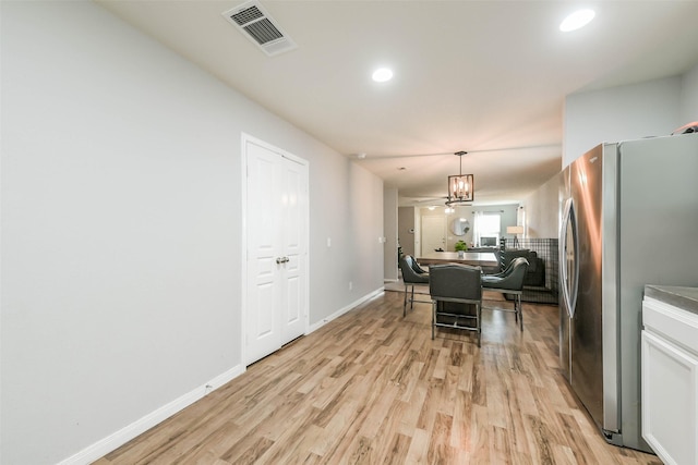 dining area featuring ceiling fan with notable chandelier and light wood-type flooring