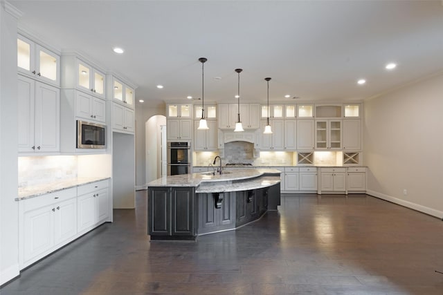 kitchen featuring pendant lighting, white cabinets, a center island with sink, dark hardwood / wood-style floors, and stainless steel appliances