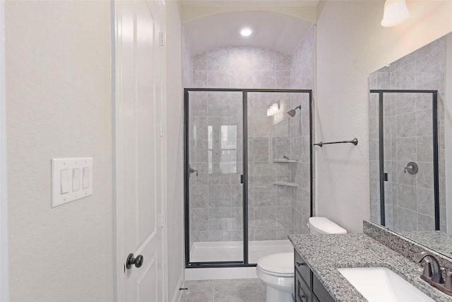 bathroom featuring tile patterned flooring, vanity, toilet, and a shower with door