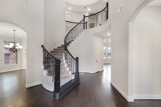 foyer entrance with a chandelier, a towering ceiling, and dark wood-type flooring