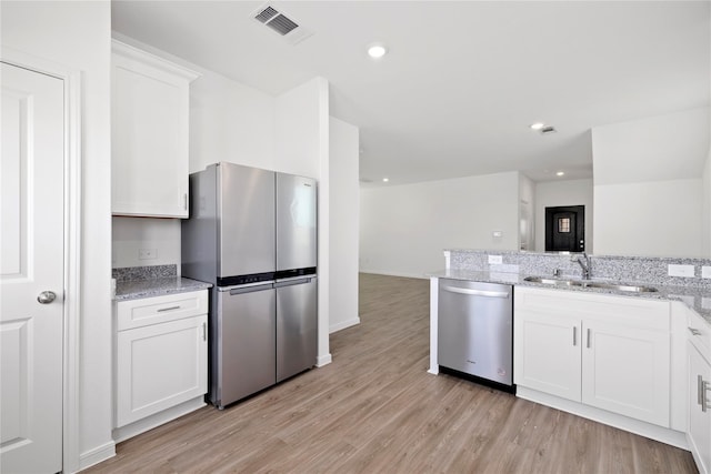 kitchen with appliances with stainless steel finishes, light hardwood / wood-style floors, white cabinetry, and sink