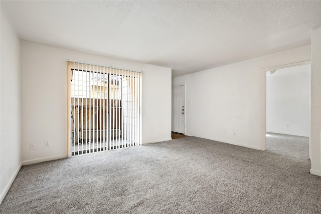 carpeted spare room featuring baseboards and a textured ceiling