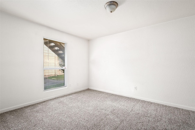 carpeted empty room featuring baseboards