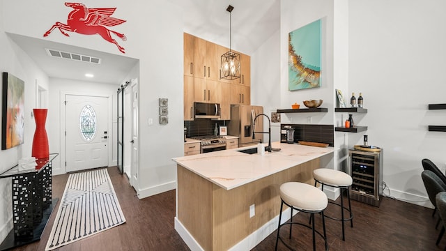 kitchen featuring a kitchen bar, appliances with stainless steel finishes, beverage cooler, dark wood-type flooring, and decorative light fixtures