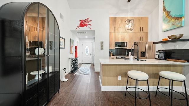 kitchen with sink, dark wood-type flooring, stainless steel appliances, tasteful backsplash, and decorative light fixtures