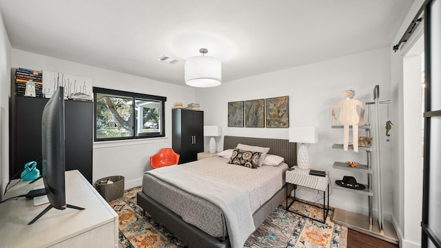 bedroom featuring a barn door and hardwood / wood-style flooring