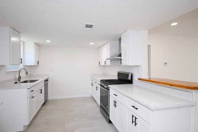 kitchen featuring sink, a textured ceiling, appliances with stainless steel finishes, white cabinetry, and extractor fan