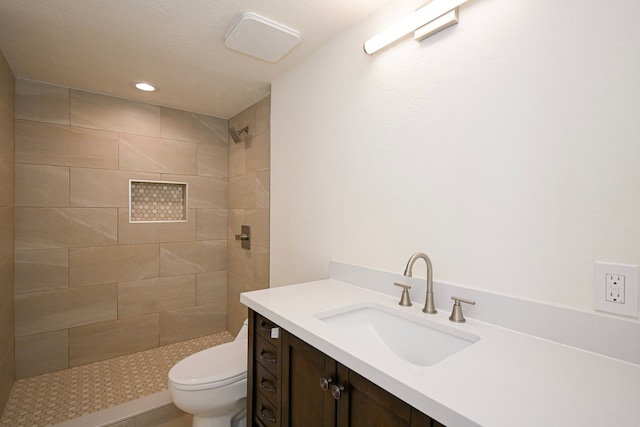 bathroom featuring vanity, toilet, and tiled shower