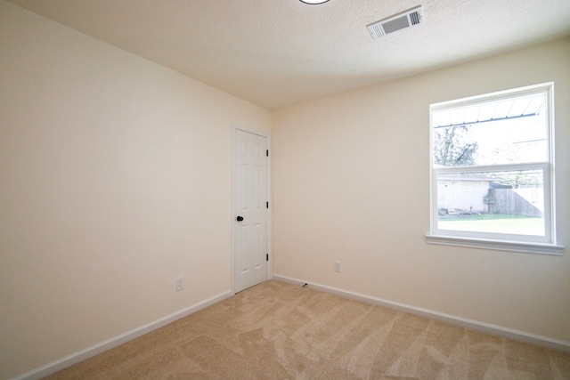 empty room featuring light colored carpet and a textured ceiling