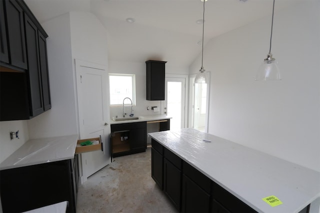 kitchen featuring vaulted ceiling, light countertops, hanging light fixtures, and a sink