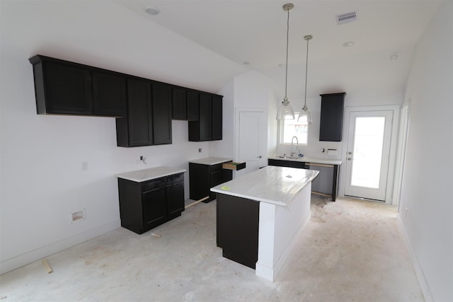 kitchen featuring visible vents, a kitchen island, decorative light fixtures, light countertops, and a sink