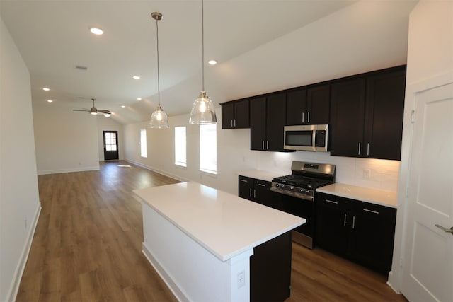 kitchen featuring wood finished floors, lofted ceiling, stainless steel appliances, light countertops, and a center island