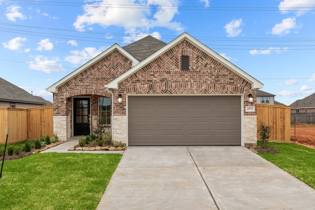 4973 Perennial Ln, La Marque, TX 77568 - view of front of house with brick siding, stone siding, concrete driveway, and fence