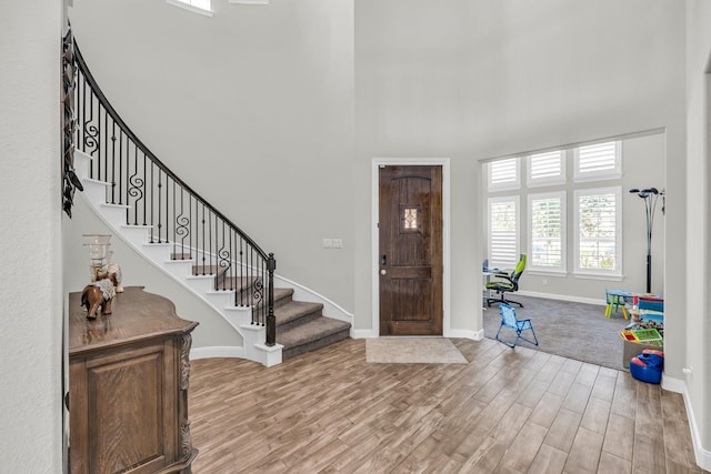 entryway with wood-type flooring and a towering ceiling