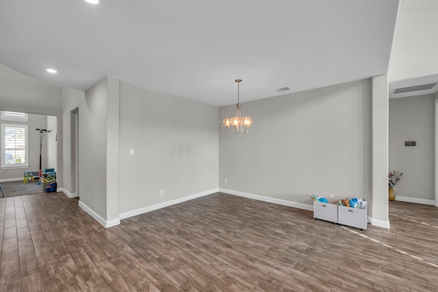 empty room with hardwood / wood-style flooring and a notable chandelier