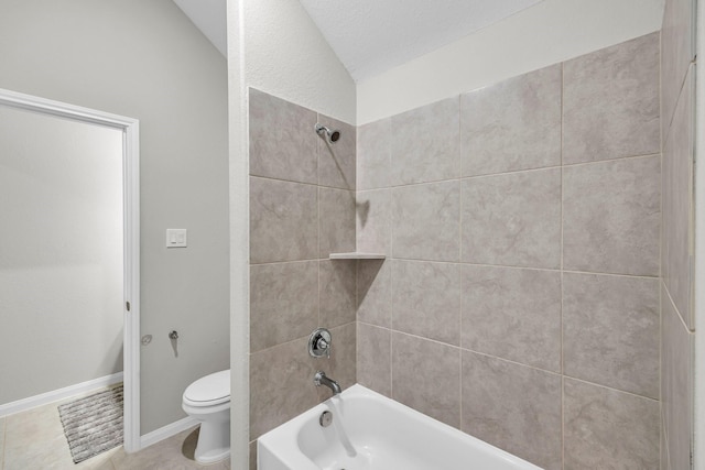 bathroom with tile patterned floors, vaulted ceiling, toilet, and tiled shower / bath