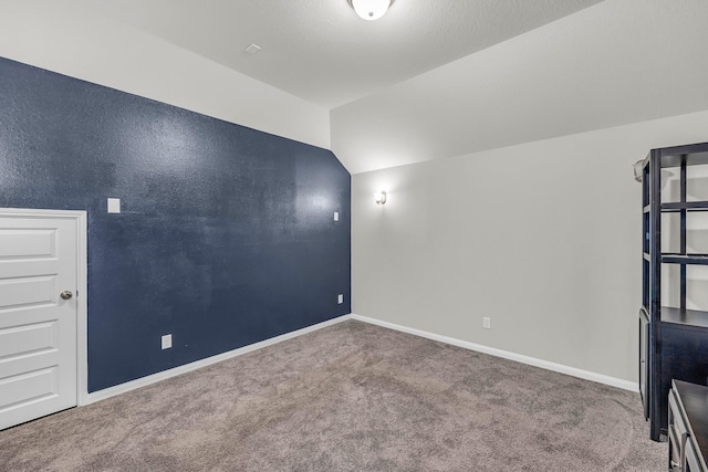 carpeted spare room with vaulted ceiling