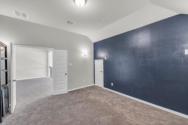 unfurnished room with carpet flooring and vaulted ceiling