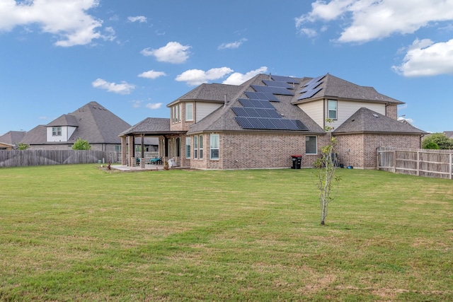 back of property featuring a lawn, a patio, and solar panels