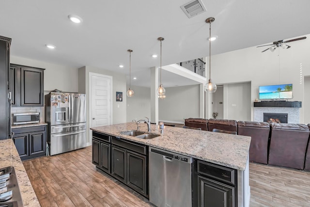 kitchen with ceiling fan, sink, hanging light fixtures, a center island with sink, and appliances with stainless steel finishes