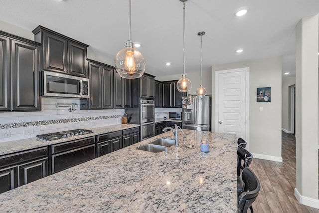 kitchen featuring pendant lighting, backsplash, sink, a breakfast bar area, and stainless steel appliances