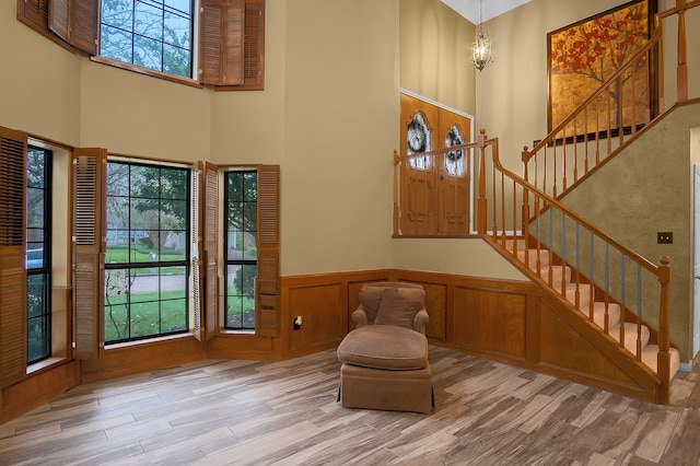 entryway featuring hardwood / wood-style floors, an inviting chandelier, wood walls, and a high ceiling