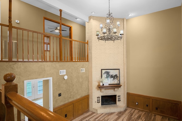 staircase featuring hardwood / wood-style flooring, ceiling fan with notable chandelier, and a fireplace