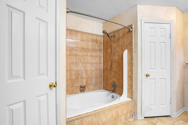 bathroom featuring a textured ceiling and tiled shower / bath