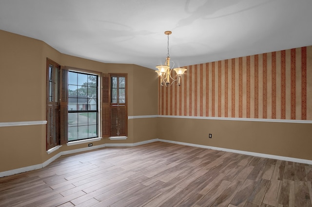 spare room featuring a notable chandelier and light hardwood / wood-style floors