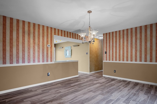 empty room featuring a chandelier and hardwood / wood-style floors