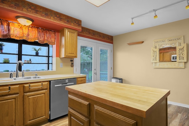 kitchen with butcher block counters, sink, french doors, stainless steel dishwasher, and light hardwood / wood-style floors