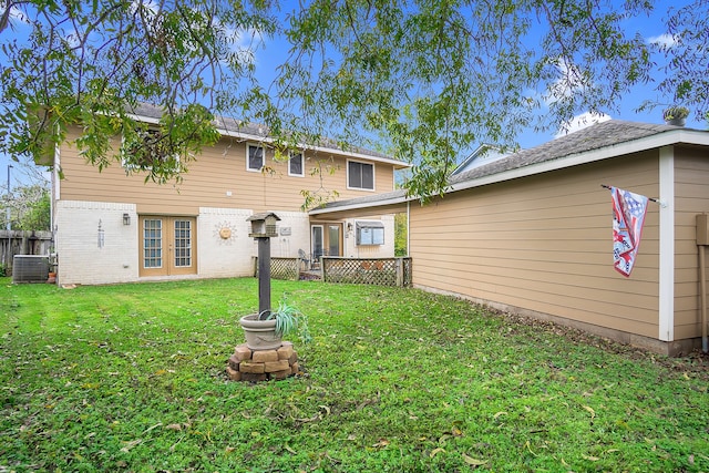 back of house featuring a lawn and central air condition unit