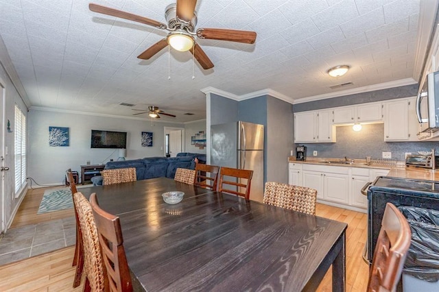 dining space featuring ornamental molding, sink, and light hardwood / wood-style flooring