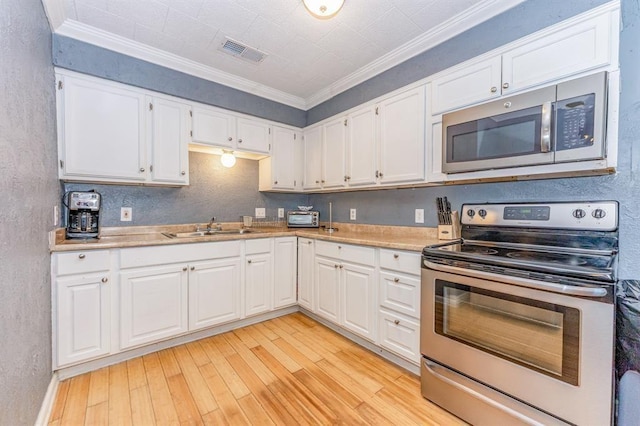 kitchen with white cabinetry, crown molding, light wood-type flooring, and appliances with stainless steel finishes