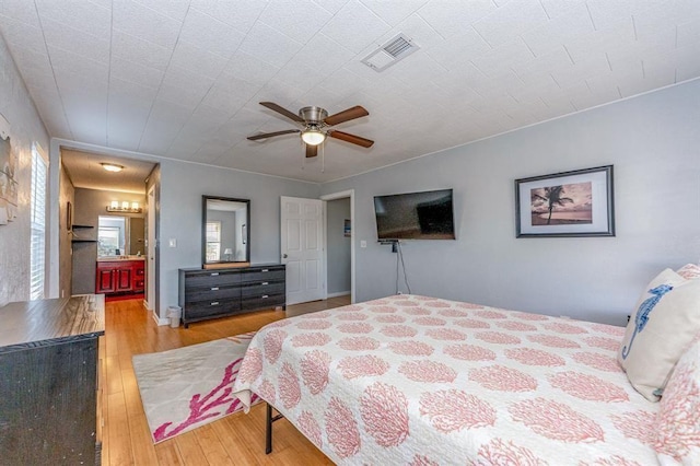 bedroom with connected bathroom, light hardwood / wood-style flooring, and ceiling fan